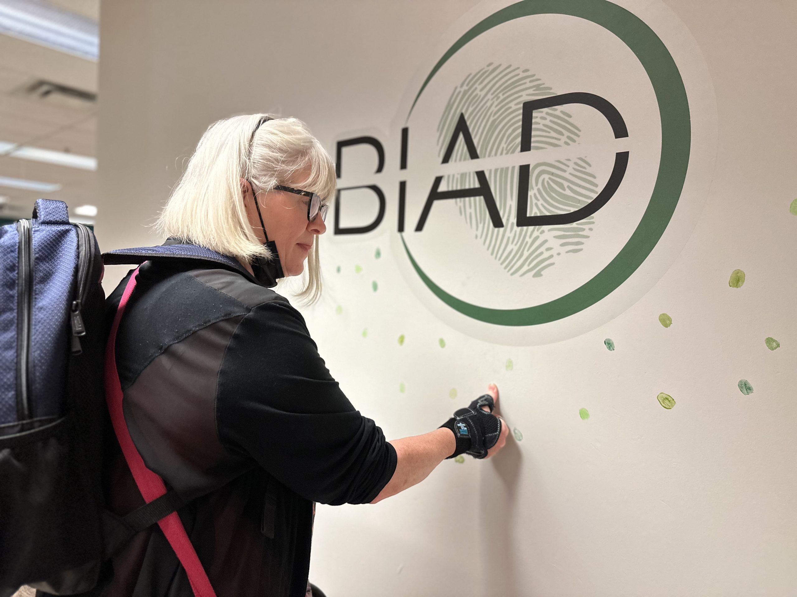 Women placing her thumb print under a large green BIAD logo on the wall/